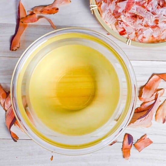 Katsuo (bonito flake) dashi in a glass bowl surrounded by bonito flakes