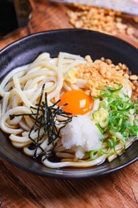 lifting mixed bukkake udon with black chopsticks