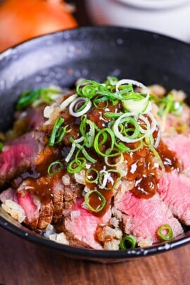 Chaliapin steak don made with slices of marinated steak cooked rare served over umeboshi and shiso rice and drizzled with an glossy gravy and chopped green onions