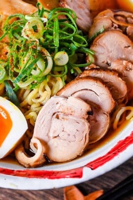 Homemade chicken chashu served on top of shoyu ramen in a white and red bowl