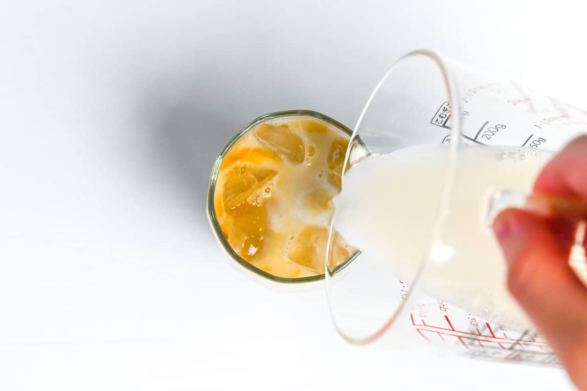 adding milk to iced hojicha latte