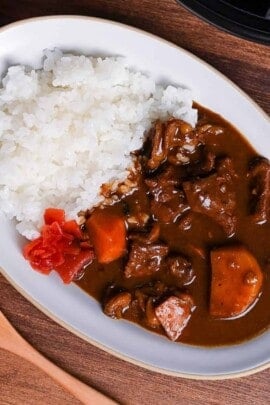 Homemade Japanese beef curry rice from scratch served on a white oval plate with fukujinzuke pickles
