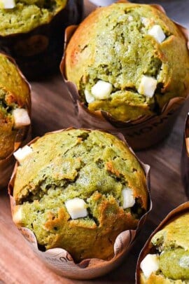 Matcha muffins with white chocolate chips on a wooden chopping board
