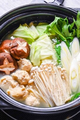 Hakata Chicken Mizutaki in a hot pot with homemade chicken meatballs, enoki, shiitake, cabbage, mizuna and spring onion in a rich chicken and kombu broth