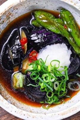 nasu no agebitashi served in a cream bowl and topped with grated daikon and chopped spring onion