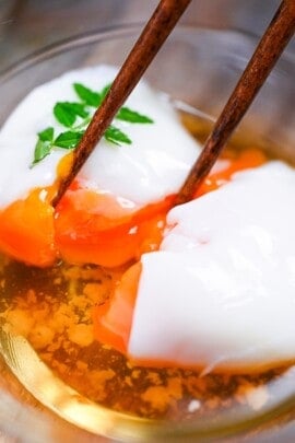 breaking apart onsen tamago (Japanese hot spring egg) with chopsticks to reveal silky yolk