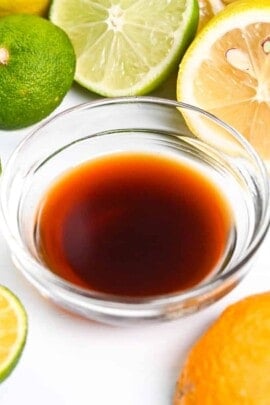 Ponzu sauce in a small glass bowl surrounded by citrus fruits