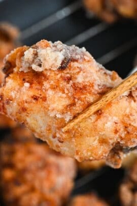 close up of complete double fried shio koji karaage Japanese fried chicken held up with chopsticks
