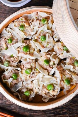 "Shumai" steamed pork dumplings in a bamboo steamer next to soy sauce and karashi mustard