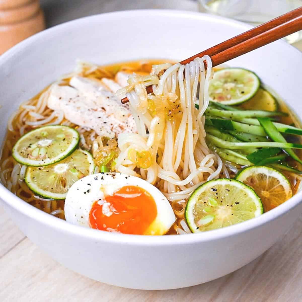 Chicken and citrus somen noodle soup in a white bowl with slices of sudachi