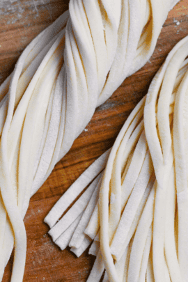 twisted bunch of homemade udon noodles on a floured wooden chopping board